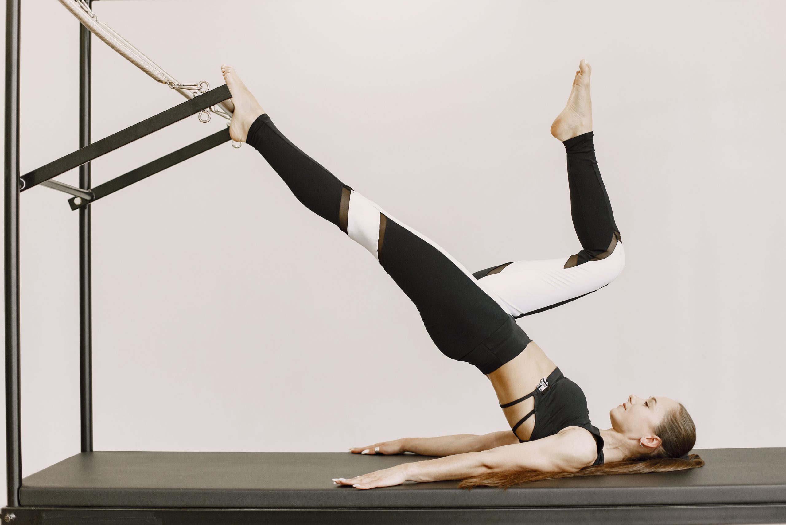 Young fit woman training in gym. Woman wearing black sportwear. Caucasian girl stretching with equipment.